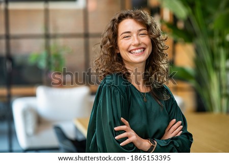 Portrait of young smiling woman looking at camera with crossed arms. Happy girl standing in creative office. Successful businesswoman standing in office with copy space. Stock foto © 