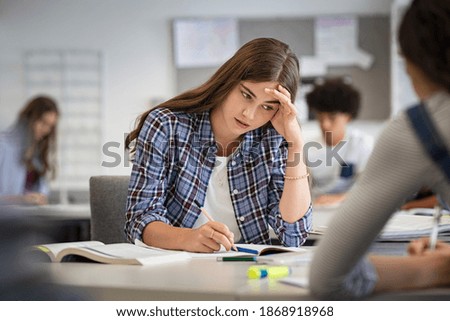 Anxious young woman with hand on head feeling tired while studying at school. College student suffering from headache in classroom. Troubled and stressed girl doing exam that doesn’t know the answers. Stock foto © 