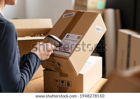 Hands scanning barcode on delivery parcel. Worker scan barcode of cardboard packages before delivery at storage. Woman working in factory warehouse scanning labels on the boxes with barcode scanner. ストックフォト © 