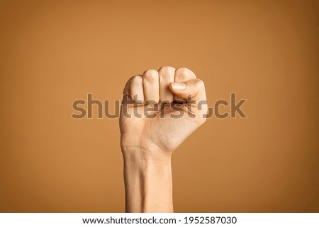 Woman hand making fist sign fighting for her rights. Hand with fingers folded into fist isolated on brown background. Fighting for women rights, against the violence and for equality and independence. Foto d'archivio © 
