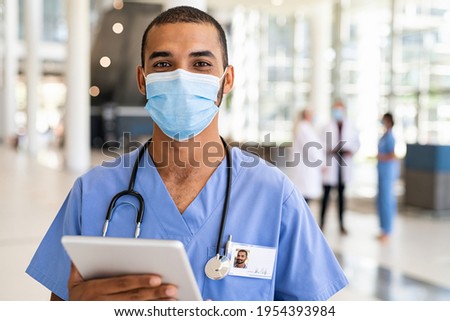 Portrait of multiethnic doctor using digital tablet wearing safety surgical face mask at private clinic during covid pandemic. Successful smiling indian nurse wearing mask for safety against covid-19 