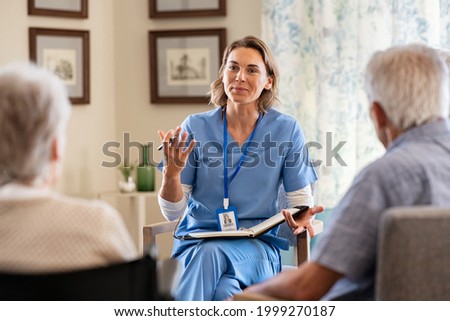 Nurse explaining to seniors at nursing home. Group of old men and women listening to young nurse on the change of therapy. Psychological support with counsellor therapist for a group of elderly people Photo stock © 