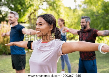 Group of multiethnic mature people stretching arms outdoor. Middle aged yoga class doing breathing exercise at park. Beautifil women and fit men doing breath exercise together with outstretched arms.  Foto d'archivio © 