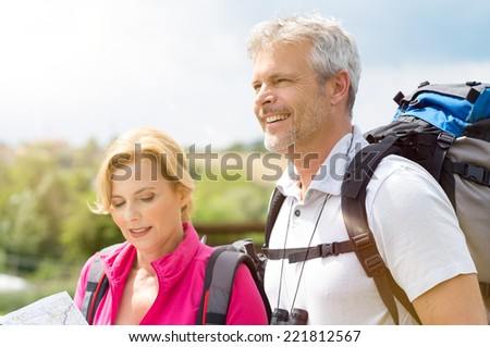 Portrait Of Happy Hikers Analyze The Map In Footpath
