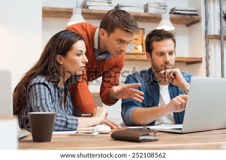 Businessman and woman discussing together while looking at laptop in office