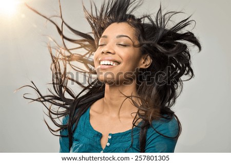 Closeup of smiling young woman blowing her hair in the wind