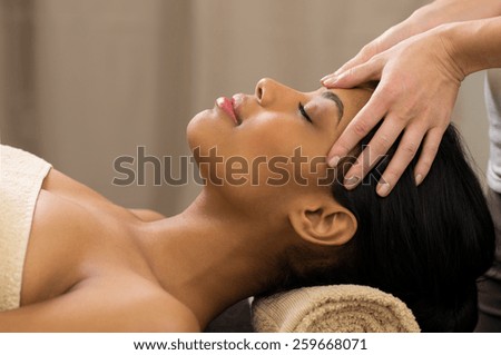 Closeup of young woman receiving professional head massage at spa