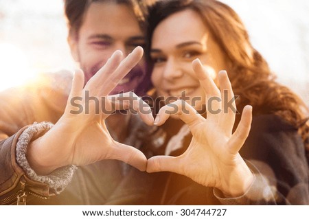 Photo of Closeup of couple making heart shape with hands