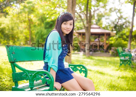 Attractive young asian woman sitting on bench, Beautiful girl in park summer portrait