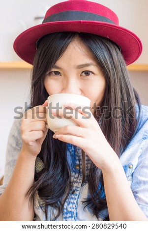 Lovely asian woman drinking coffee in vintage cafe , Fashionable holding coffee look at camera