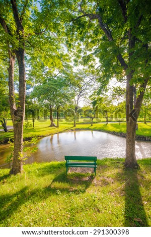 Bench sit in beautiful meadow green park in front of pond, Empty park bench with lake