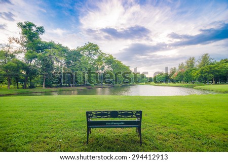 Bench sit in beautiful meadow green park in front of pond, Empty park bench with lake