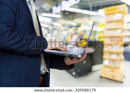 Close up of business man with a laptop in book store background