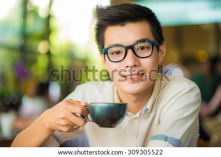 Young asian guy drinking coffee while computing at a student cafe