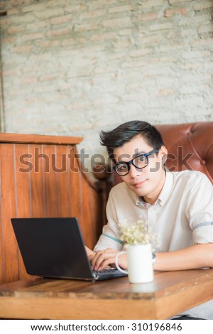 Young asian man drinking coffee in cafe and using laptop computer, Art coffe shop
