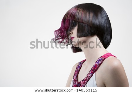 Caucasian woman with closed eyes and extravagant hairstyle - pink strands over the face. Side view. In studio.
