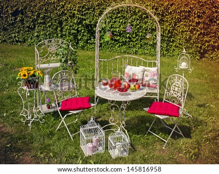 Decorative garden with white furniture and picnic table in the summer.