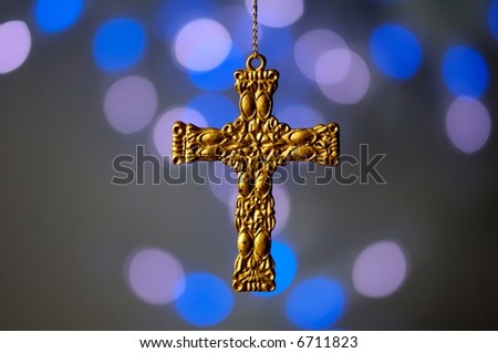 Image of a gold cross hanging in front of out of focus lights