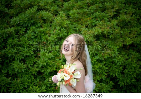 An image of a laughing bride against lush foliage
