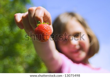 Young girl holding a strawberry in hand