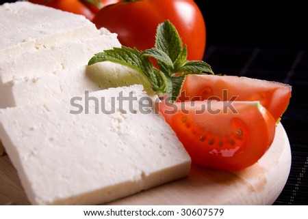 Slices of fresh white cheese with tomato and mint leaves