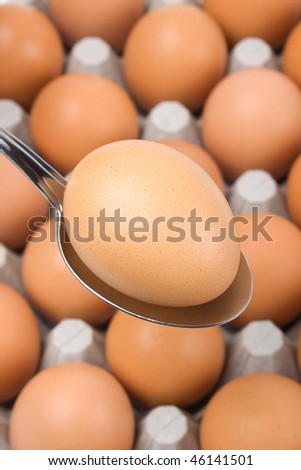 Chicken egg in a spoon over more eggs as background