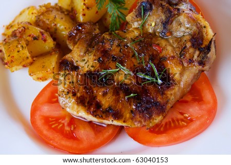 Grilled pork loin chop with baked potato and tomato
