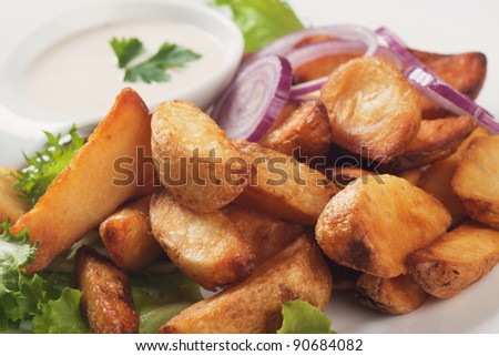 Fried potato wedges with white sauce and lettuce
