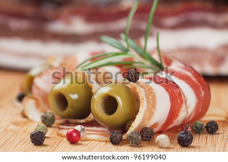 Rolls of smoked bacon with rosemary, olives and peppercorn