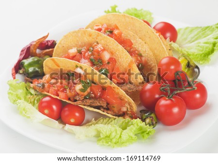 Taco shells filled with grilled meat and fresh vegetable salsa