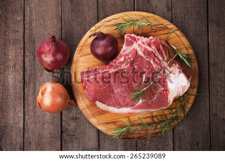 Raw ribeye beef steak on wooden board, overhead shot