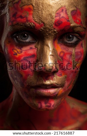 young woman with creative face-art and flow paint over black background