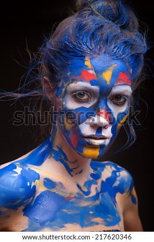 Beautiful face of a woman covered in paint Close up of a woman\'s face covered in blue, red and purple paint