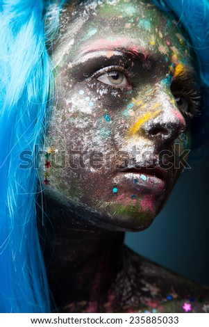 Blue hair. Woman with face art and body art. Painted girl portrait on dark background.