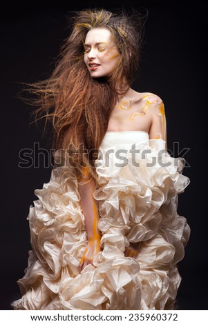 Woman in wedding dress. Young attractive and smiling Bride posing in studio. Luxury dress. Creative face art on face.  Curly hair.