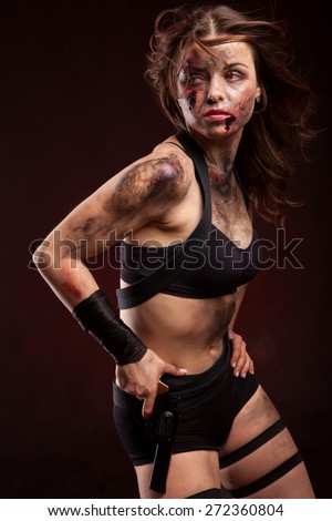 Beautiful sexy girl with gun. Posing in studio. With blood on face and wound.