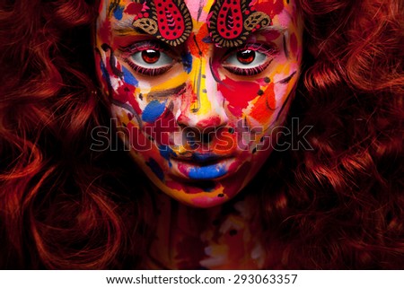 Young woman with bush of red curly hair bright face art and glowing brown eyes