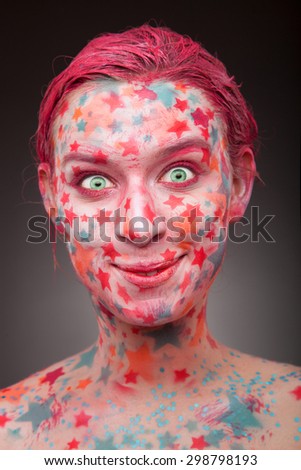 Emotional portrait of a young extremely happy, joyful woman with stars on the face and painted hair in pink  with stars on the face