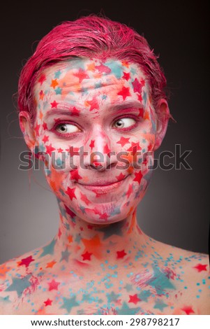 Emotional portrait of a happy, glad young woman with stars on the face and painted hair in pink