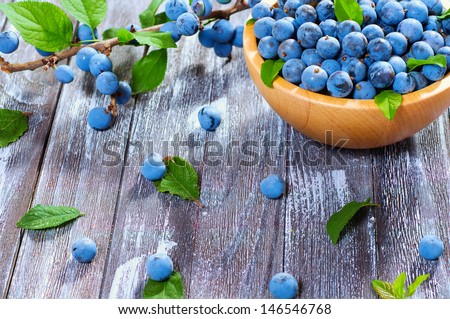 Wild berry thorn on a beautiful wooden background surrounded by green foliage