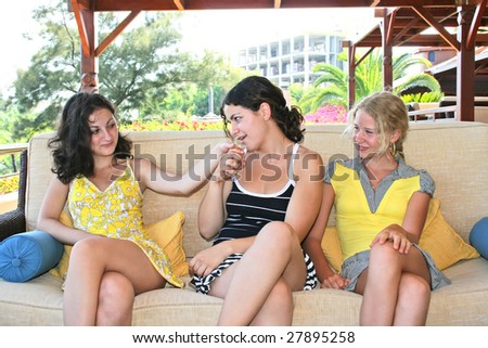 Pretty blond and brunette girls having fun on the sofa.