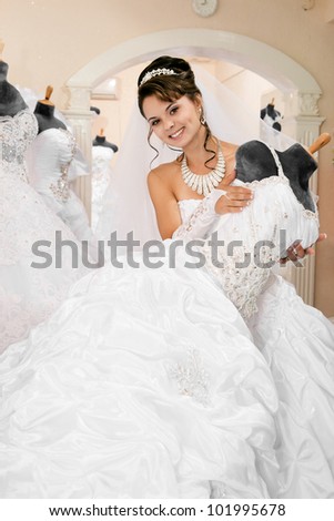 pretty young excited woman is choosing a wedding dress in the shop