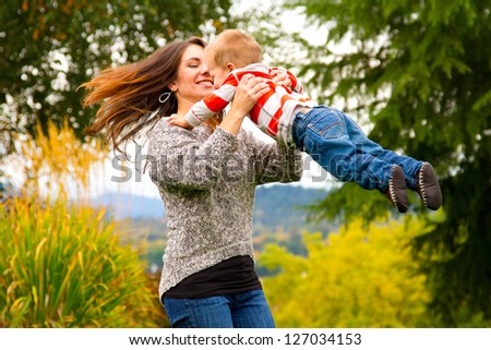 A woman spins her child around while holding him in the air in this joyous happy moment.