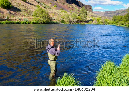 An experienced fly fisherman wades in the water while fly fishing the Deschutes River in Oregon.