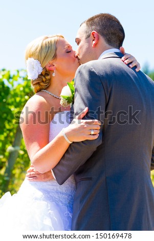 A bride and groom share a romantic kiss on their wedding day at a winery vineyard in oregon.