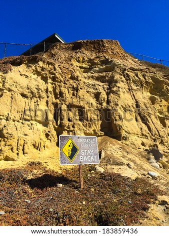 California cliffs are deemed unstable and there is a danger sign warning of the issue with a house above at this beach.