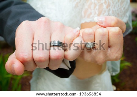 Bride and groom put their hands together in the pinky swear position to show off their wedding rings after the ceremony.