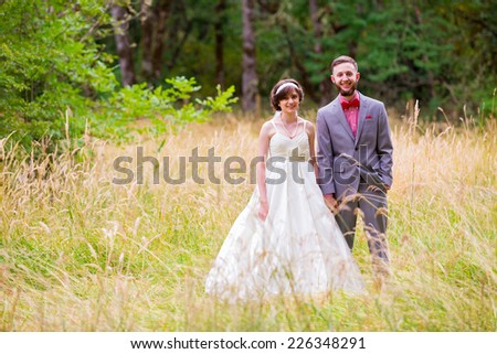Wedding day portrait of the bride and groom in a field before their ceremony.