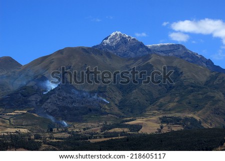 The dormant volcano, Mount Cotacachi, with a forest fire on its slope near the town of Cotacachi, Ecuador