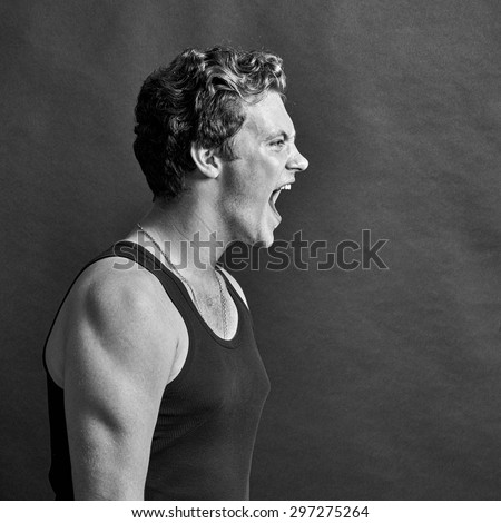 Black and white portrait of a man screaming on a gray background